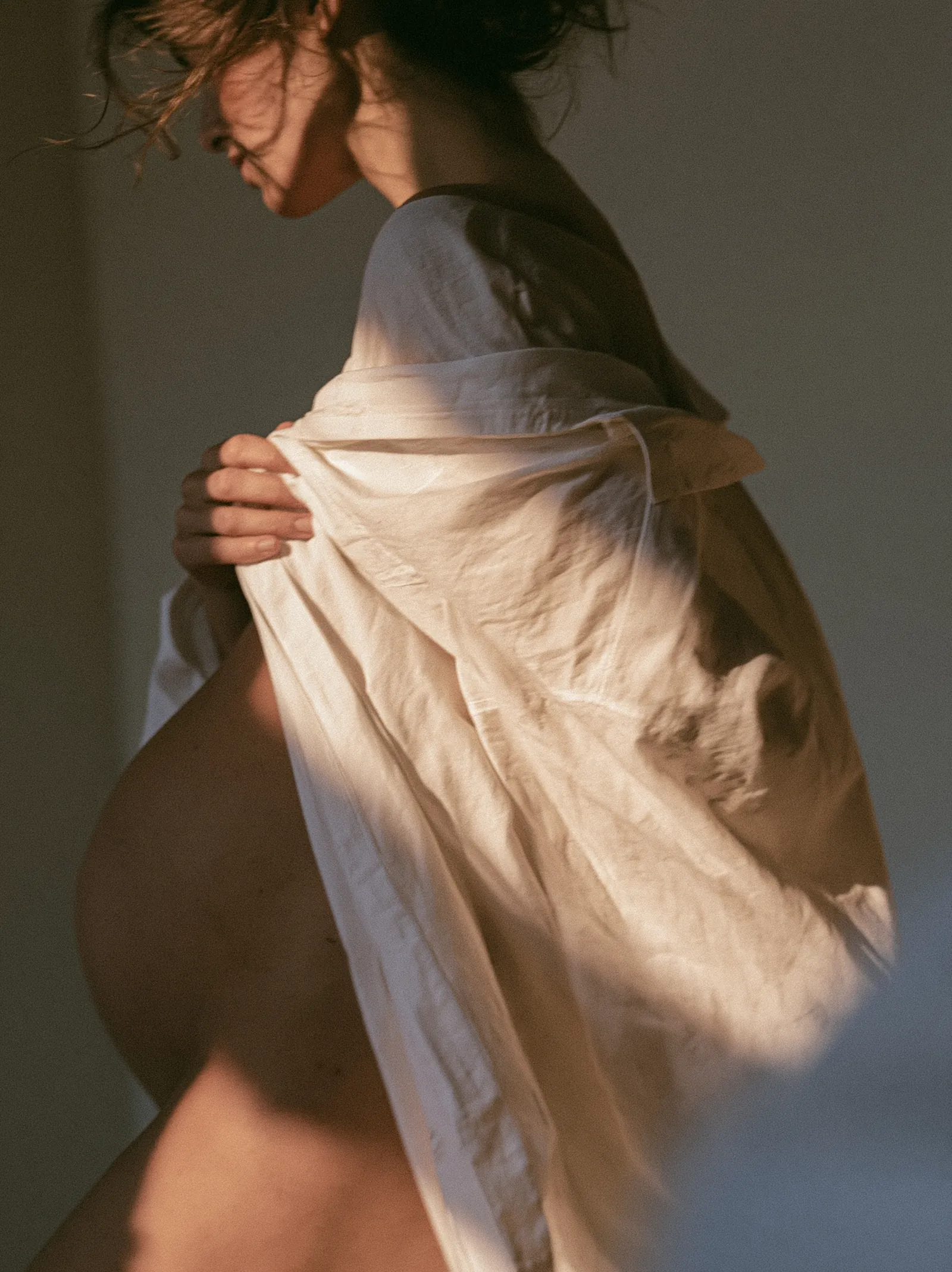 Pregnant woman in a white shirt lit by late afternoon window light at home in Santa Monica